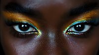 Close up view of eyes with vibrant turquoise and gold glitter eyeshadow makeup on dark skin, dramatic beauty portrait showcasing artistic cosmetic application and intense gaze.