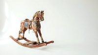 Antique wooden rocking horse with worn paint and leather saddle, isolated on white background, evoking nostalgia and vintage childhood charm.
