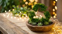 Green moss letter G in wooden bowl with warm fairy lights creating cozy holiday atmosphere on rustic wood table for seasonal home decor and crafting projects.