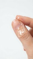 Close-up of a hand holding a clear gel or serum droplet against a white background, showcasing skincare product texture and consistency for cosmetic and beauty applications.