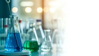 Laboratory glassware with colorful chemical solutions on research table. Scientific equipment for experiments, analysis and pharmaceutical development.
