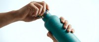 Male hands opening teal water bottle cap against white background for hydration and fitness lifestyle concepts.