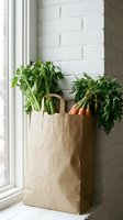 Fresh organic vegetables in brown paper bag by window with white brick wall background for healthy grocery shopping and sustainable living.