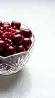 Fresh dark red cherries and pomegranate seeds in crystal bowl on white background. Isolated fruit arrangement suitable for food, nutrition, and healthy eating designs.