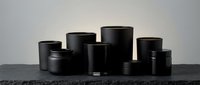 Black cosmetic jars and containers collection on dark surface for skincare packaging and beauty product branding mockup design.