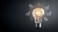 Glowing light bulb with brain filament surrounded by growth arrows and gears on dark background representing innovation and creative business solutions.