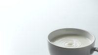 Gray ceramic coffee cup with creamy white milk swirl pattern on clean white background isolated for design projects and commercial use.