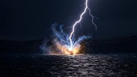 Lightning strike hitting ocean water creating dramatic explosion with sparks and steam against dark stormy sky for weather and nature concepts.