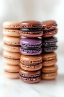 Stack of colorful French macarons in shades of brown, purple, and peach on marble background, with selective focus creating dreamy depth of field effect.