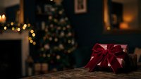 Red gift box with ribbon bow on wooden surface, festive holiday decoration with blurred Christmas tree and warm golden lights in background, seasonal celebration scene.