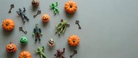 Halloween flat lay with miniature pumpkins, skeleton keys, and spooky toy figures arranged on neutral background for seasonal crafting and decoration projects.