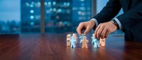 Businessman arranging paper family figures on wooden desk with city skyline background, representing insurance, protection, planning, and financial security for loved ones.