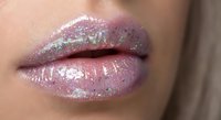 Close-up of glossy pink lips with holographic glitter makeup creating iridescent shimmer effect for beauty and cosmetics advertising campaigns.