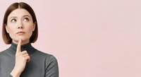 Woman with hand on chin looking upward in thoughtful pose against pink background, expressing contemplation and decision-making for business and lifestyle concepts.
