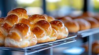 Fresh baked brioche buns with glossy golden brown crust arranged on cooling rack, showing soft texture and professional bakery quality. Selective focus.