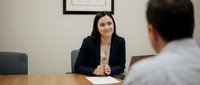 Professional Asian businesswoman conducting job interview in modern office meeting room with male candidate across conference table.