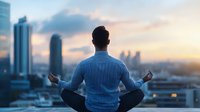 Young Asian businessman meditating in lotus position on rooftop during sunset, city skyline background shows work-life balance and mindfulness practice.