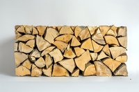 Neatly stacked firewood logs arranged in rows showing natural wood grain pattern and textures against white background, ready for winter heating season.