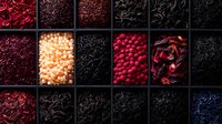 Assorted dried flowers, petals and botanicals arranged in wooden compartment box display, featuring vibrant red, pink, white and dark tones for natural crafts and potpourri.