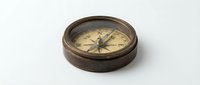 Vintage brass compass with aged patina on white background, antique navigation instrument for maritime adventures and exploration themes.