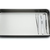 Stainless steel medical tray with surgical instruments including scalpel, forceps and tweezers for healthcare procedures and sterile operations.