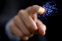 Finger touching glowing digital point with spreading blue particles effect on dark background, representing future technology and digital transformation.
