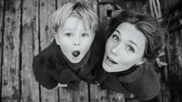Two children looking up with surprised expressions in black and white portrait photography. Young siblings with blonde hair showing amazement and wonder.