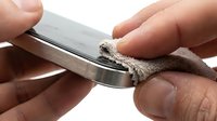 Hands cleaning a metal nail file with a cloth, removing dust and debris for maintenance and hygiene purposes.