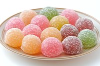 Colorful sugar-coated jelly candies arranged on glass plate, sweet gummy treats in rainbow colors for confectionery and dessert concepts.