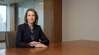 Professional businesswoman executive sitting at conference table in modern corporate office boardroom during business meeting.