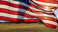 American flag waving in wind against blue sky background, patriotic symbol of freedom and independence for national holidays and celebrations.