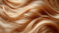 Luxurious wavy blonde hair texture with golden highlights and caramel tones. Close-up of smooth, shiny strands creating flowing pattern for beauty and haircare industry.