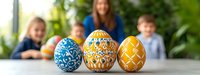 Colorful decorated Easter eggs in blue and yellow patterns with blurred family background celebrating spring holiday traditions and festivities.