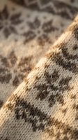Close-up macro shot of beige and brown knitted wool fabric with geometric pattern showing detailed textile fibers and weave structure for fashion design projects.