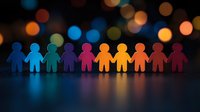 Colorful paper cutout figures holding hands in unity against dark background with bokeh lights, symbolizing diversity, inclusion and community spirit.
