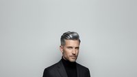 Middle-aged man with gray hair and facial hair wearing black turtleneck against neutral background for portrait and professional use.
