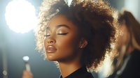 Young African American woman with natural curly afro hair and glowing skin in profile against backlit background, eyes closed in serene expression.