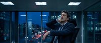 Confident businessman in suit relaxing in modern office with city skyline view at night, corporate success and leadership concept.