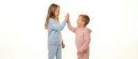 Two children giving high five in colorful pajamas on white background. Boy and girl celebrating friendship and teamwork in sleepwear for kids lifestyle.
