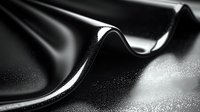 Elegant black silk fabric with gentle folds and curves creates dramatic light and shadow play on textured surface with subtle sparkle effect. Luxury fashion background.