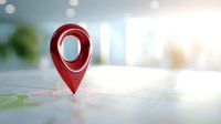 Red location pin marker on map with blurred office background, representing business navigation, destination point, or travel planning concept.