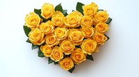 Yellow roses arranged in heart shape with green leaves on light background, romantic floral composition for wedding, anniversary or Valentine's day celebration.