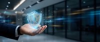 Businessman holding glowing shield icon with digital network particles, representing cybersecurity, data protection, and secure business solutions in modern office environment.