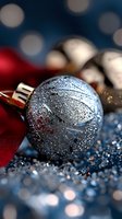 Glittering silver Christmas ornament ball with frost effect on sparkling surface, red ribbon accent against dark blue bokeh background for holiday decor.