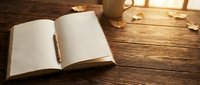Open blank notebook with pen on wooden desk near warm lamp and window light, suitable for writing, journaling, planning, and creative projects.