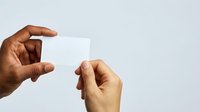 Two hands exchanging blank white business card against neutral background, suitable for corporate branding, identity design, and professional mockup projects.