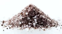 Pile of gourmet sea salt mixed with ground coffee beans on white background, creating a flavorful culinary seasoning for meat rubs and desserts.