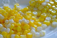 Corn kernels in yellow and white colors on white plate, fresh produce for cooking and food preparation.