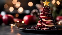 Festive dessert shaped like Christmas tree made from white chocolate and cranberries topped with golden star on dark plate against blurred holiday lights background.