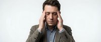 Stressed businessman in suit holding head with hands showing headache migraine pain isolated on white background for healthcare workplace wellness concepts.
